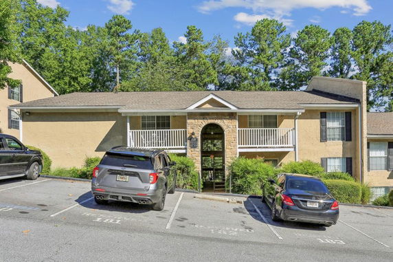 Front view of a two-story building with balconies and parking area.