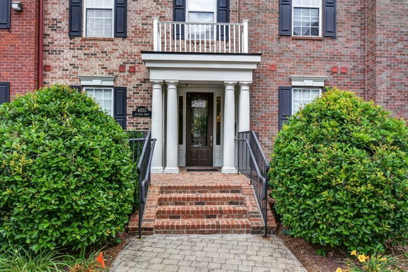 Front view of a brick house with white columns and a balcony above the entrance.