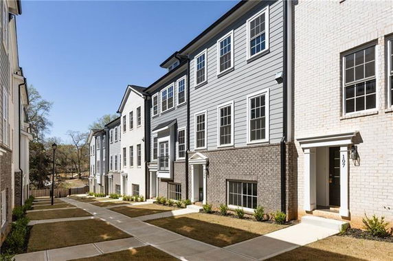 Front view of multiple modern three-story townhouses.