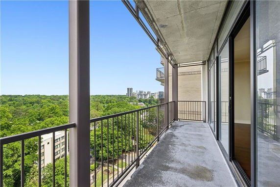 Balcony view overlooking a cityscape with tall buildings and greenery.