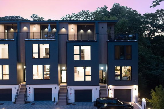 Front view of a multi-story townhouse with large windows and a garage at the ground level.