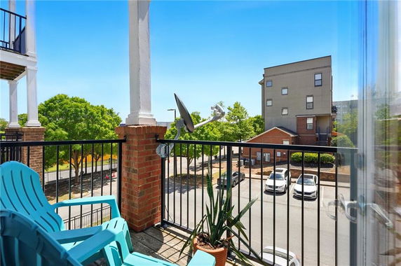 View from a balcony overlooking a residential area with parked cars and trees.