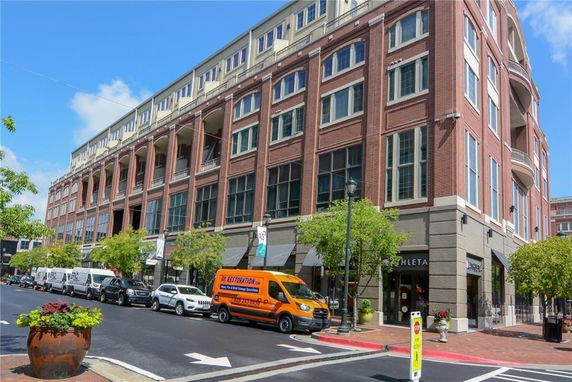 Front view of a multi-story commercial building with shops and parked vehicles.
