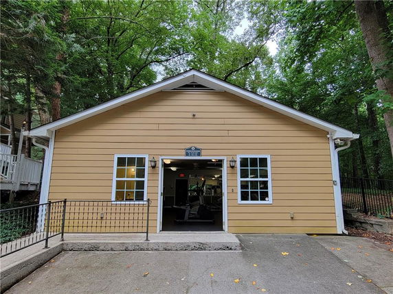 Front view of a small single-story building with yellow siding and two windows.