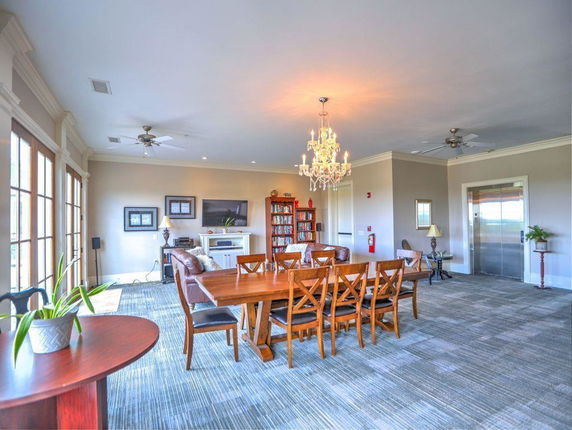 Interior view of a room with chandelier, large dining table, and seating area.