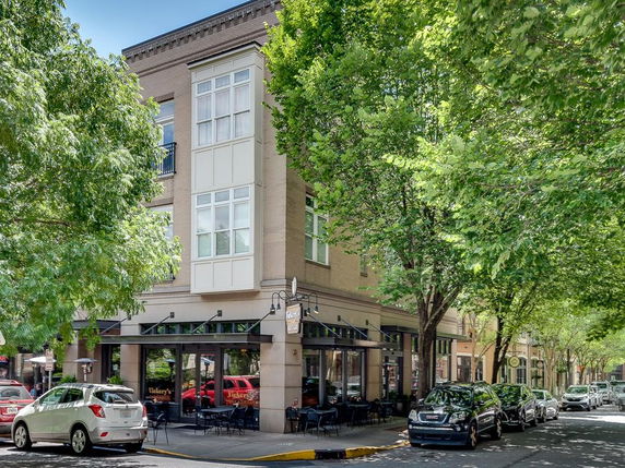 Front view of a multi-story building with street-level shops and large windows.