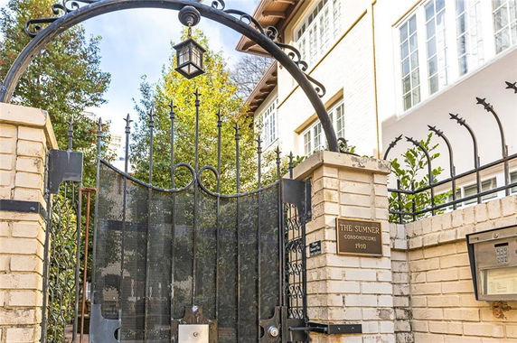 Front view of a condominium entry gate with brick pillars and a wrought iron gate.