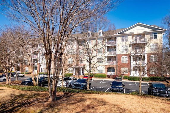Front view of a multi-story apartment building with parking.