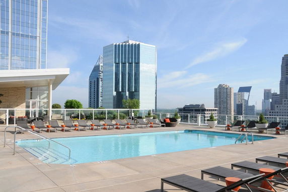 Rooftop swimming pool area with city buildings in the background.