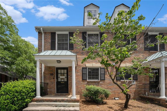 Front view of a two-story brick house with a small porch and white pillars.