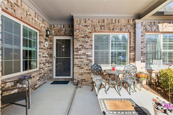 Front view of a house with brick walls and a small patio with chairs and a table.