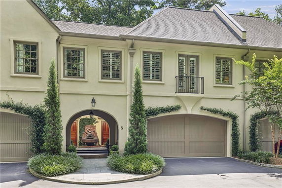 Front view of a two-story house with two garages and decorative greenery.