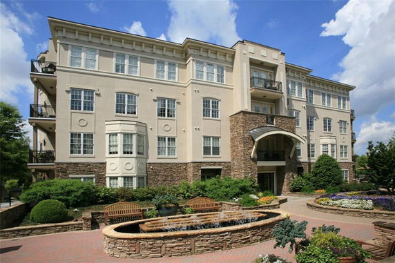 Front view of a multi-story apartment building with balconies and brick detailing.