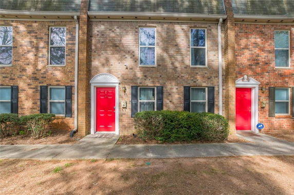 Front view of a two-story brick townhouse with red doors.