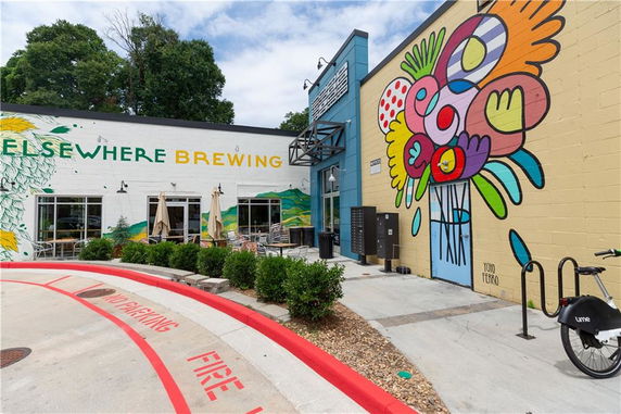Front view of a commercial building with vibrant murals and outdoor seating.