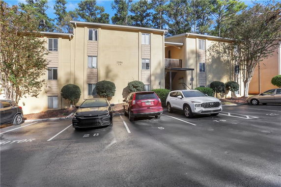 Front view of an apartment building with a parking lot.