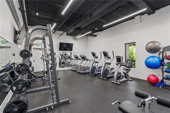 Indoor gym area with exercise equipment and weights.