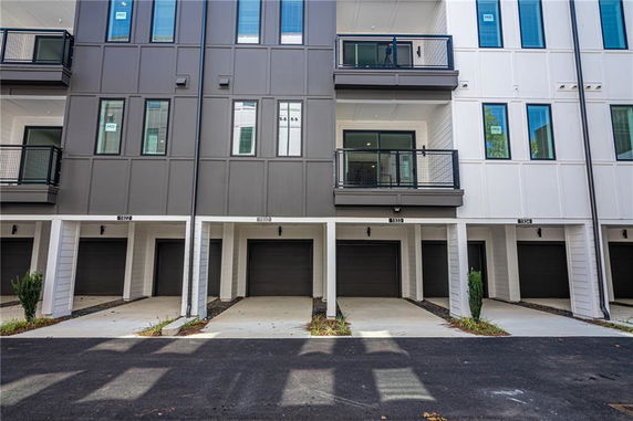 Front view of a multi-story residential building with balconies and garages.