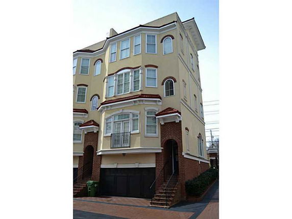 Front view of a multi-story townhouse with a garage on the ground level.