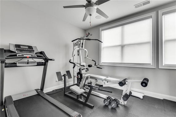 Room equipped with gym equipment including a treadmill and weight machine.