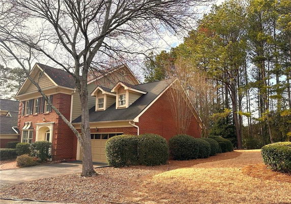 Front view of a two-story house with a garage and red brick facade.