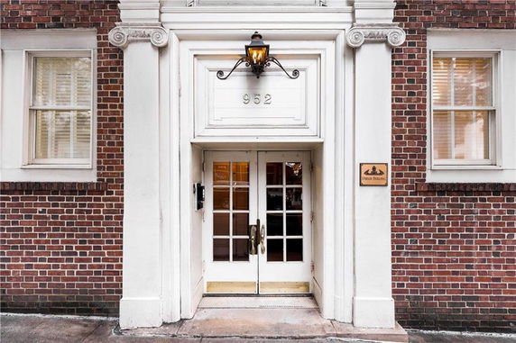 Front entrance of a brick building with a white door frame and lamp above the door.