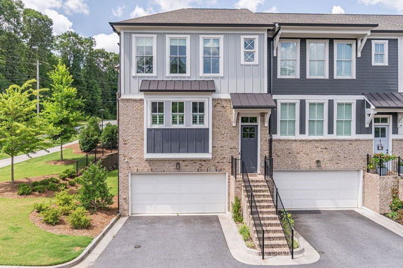 Front view of a two-story townhouse with brick and siding exterior and double garage.