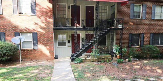 Front view of a two-story brick apartment building with a staircase and a satellite dish.