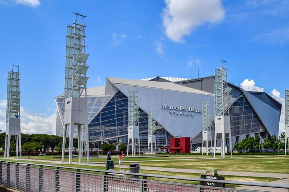 Front view of a large, modern stadium with angular design and glass facade.