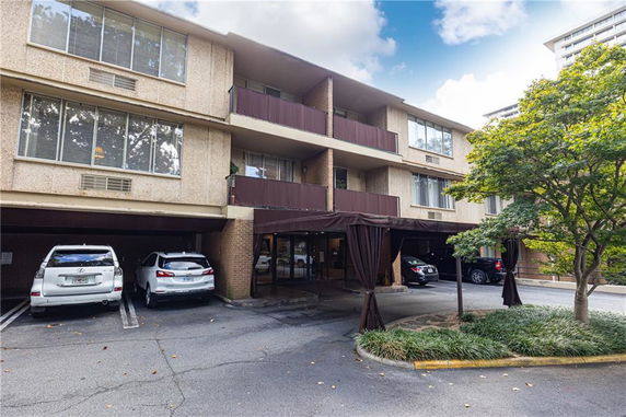 Front view of a multi-story residential building with parking spaces underneath.