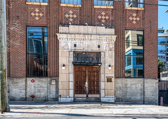 Front view of a brick building with large door and decorative patterns.