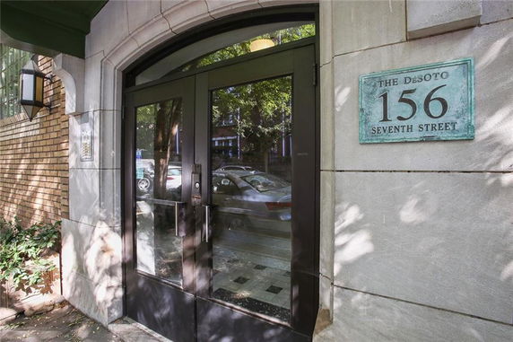 Front entrance of a building with glass doors and an address plaque.