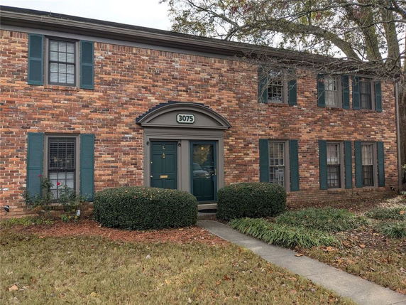 Front view of a two-story brick building with green shutters and door.