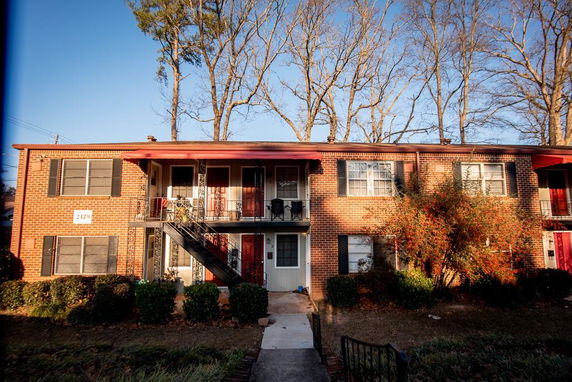 Front view of a two-story brick apartment building with external stairs.