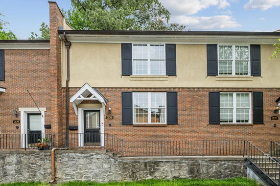 Front view of a two-story house with black shutters and a brick exterior.