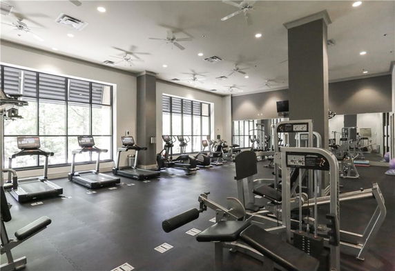 Gym area with various exercise equipment and large windows.