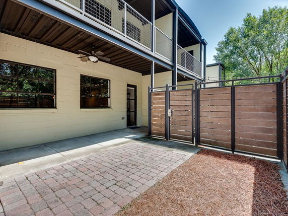 Front view of a two-story building with a wooden fence and a patio area.
