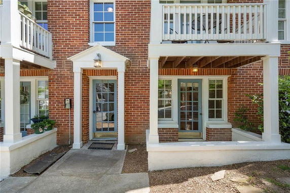 Front view of a brick house with a covered porch and glass door entry.