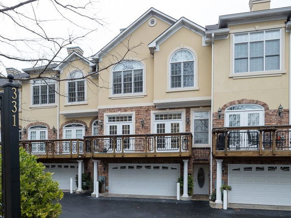 Front view of a townhouse with large windows and double garages.