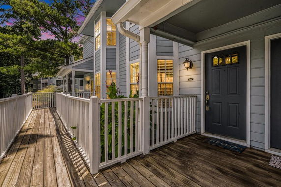 Front view of a two-story house with a wooden porch and railing.