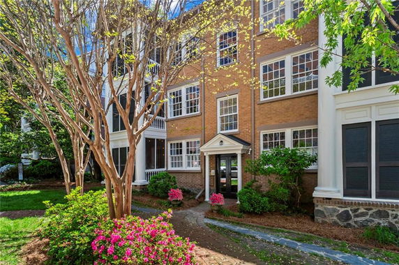 Front view of a multi-story brick house with numerous windows and a small portico entrance.