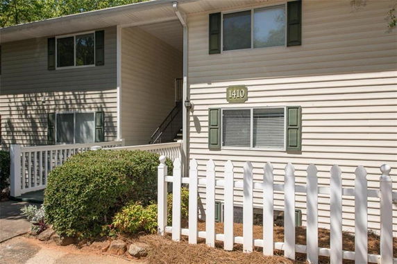 Front view of a two-story house with white siding and green shutters.