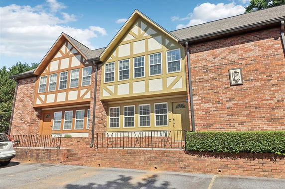 Front view of a two-story brick house with triangular roof designs.