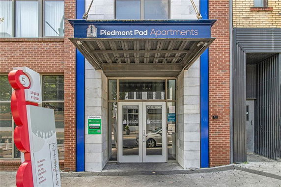 Entrance view of an apartment building with a brick facade and blue accents.