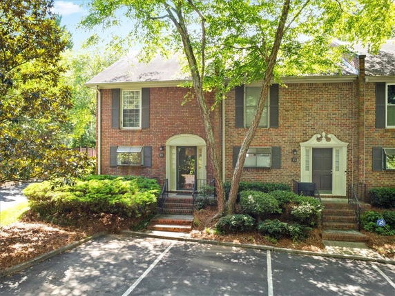 Front view of a brick townhouse with two entrances and large windows.