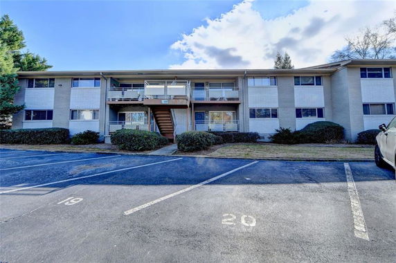 Front view of a two-story apartment building with visible parking spaces.