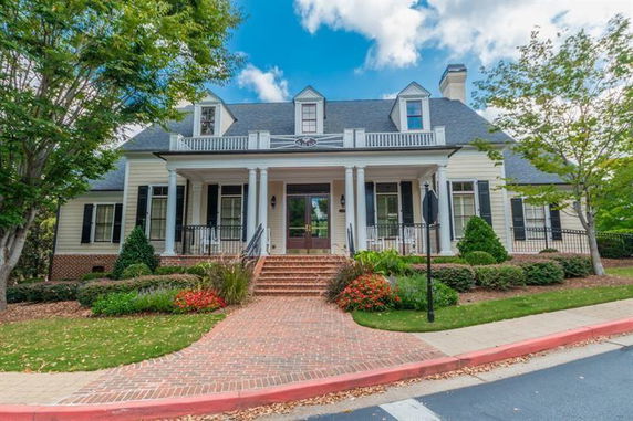 Front view of a two-story house with a wide porch and dormer windows.