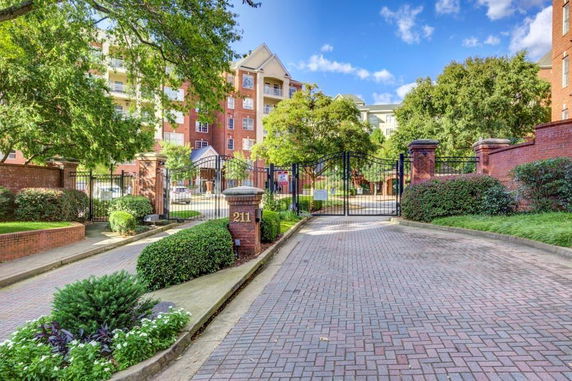 Front view of a multi-story brick building behind a gated entrance.