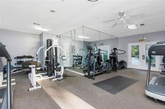 Room equipped with exercise machines and mirrored walls in a gym.