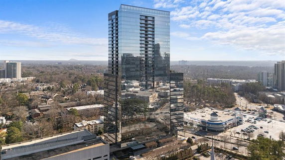 Front view of a tall, reflective glass building in an urban area.
